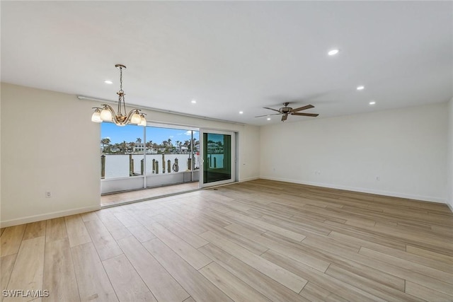 unfurnished living room with ceiling fan with notable chandelier and light hardwood / wood-style flooring