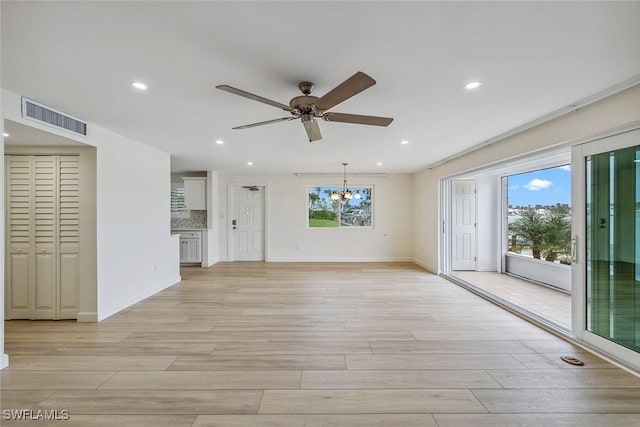 unfurnished living room featuring ceiling fan with notable chandelier and light wood-type flooring