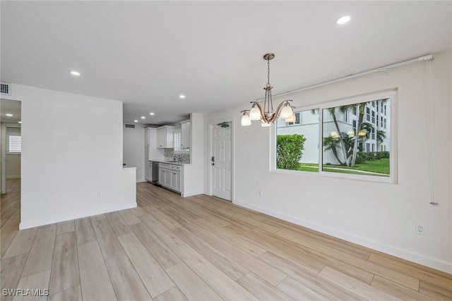 interior space with plenty of natural light, a chandelier, and light wood-type flooring