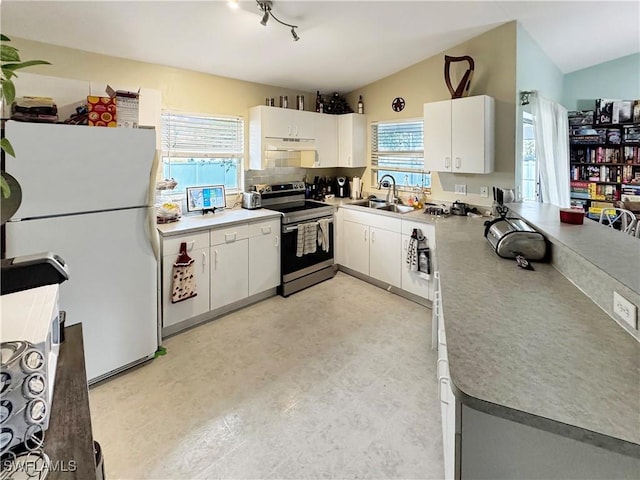 kitchen with white cabinetry, white fridge, stainless steel range with electric stovetop, sink, and vaulted ceiling