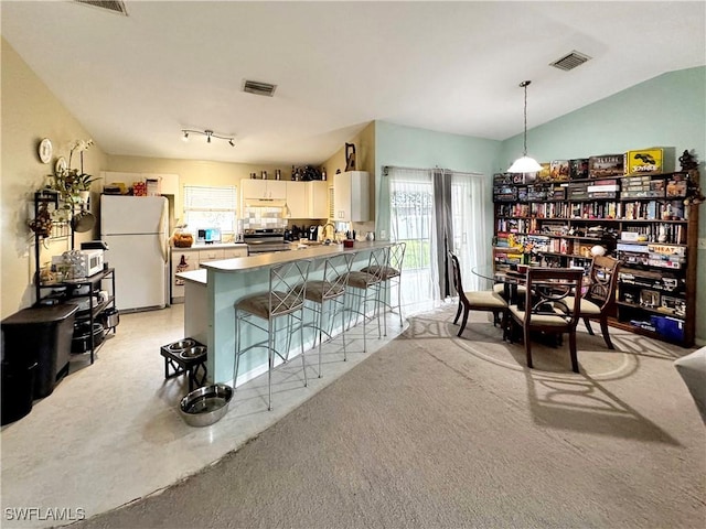 kitchen featuring stainless steel electric stove, white cabinetry, white fridge, a kitchen breakfast bar, and kitchen peninsula