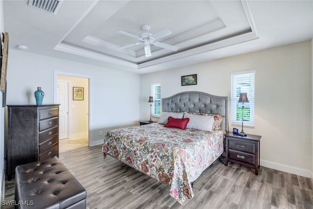 bedroom featuring a raised ceiling, multiple windows, and visible vents