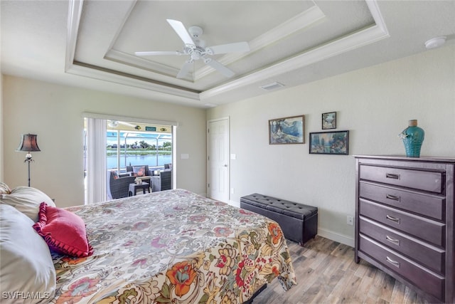 bedroom with light wood finished floors, visible vents, ceiling fan, baseboards, and a tray ceiling