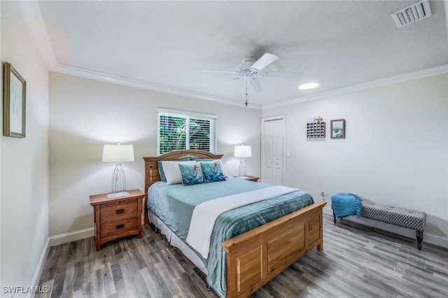 bedroom featuring visible vents, wood finished floors, baseboards, and ornamental molding