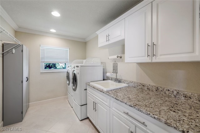 laundry room with baseboards, cabinet space, a sink, crown molding, and washing machine and dryer