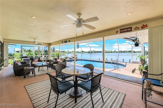 sunroom with a wealth of natural light, a water view, and a ceiling fan