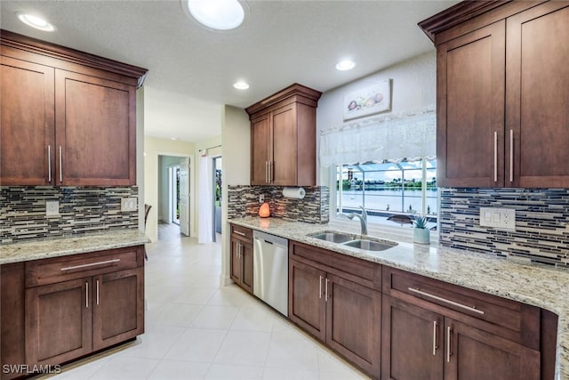 kitchen featuring light stone counters, recessed lighting, a sink, stainless steel dishwasher, and tasteful backsplash