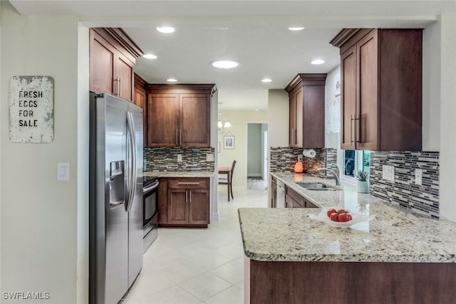 kitchen with light stone countertops, a peninsula, a sink, decorative backsplash, and appliances with stainless steel finishes