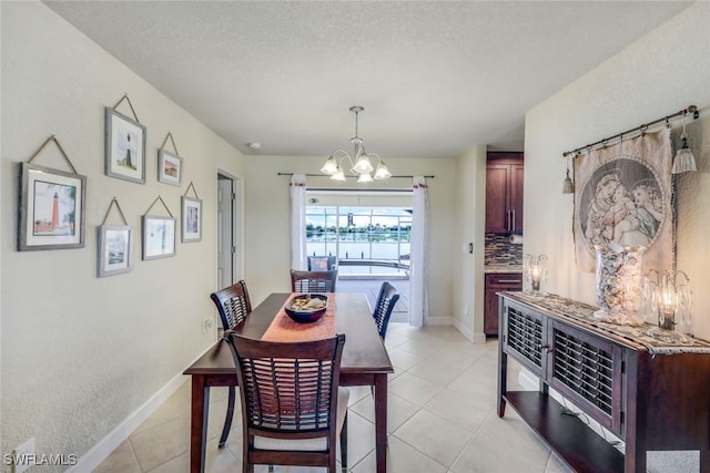 dining area with light tile patterned floors, baseboards, a textured ceiling, and an inviting chandelier