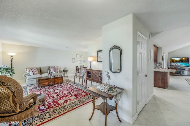 living area featuring light tile patterned floors, baseboards, a textured ceiling, and lofted ceiling