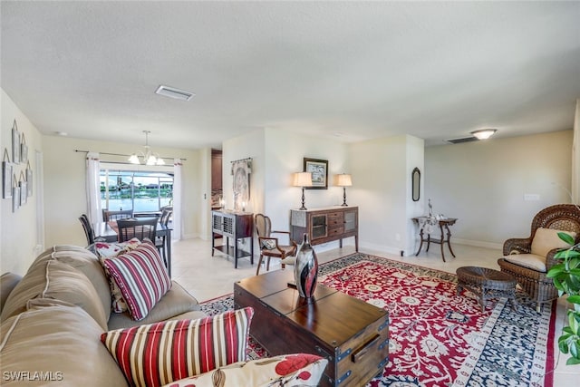 living area featuring light tile patterned floors, visible vents, a textured ceiling, and an inviting chandelier