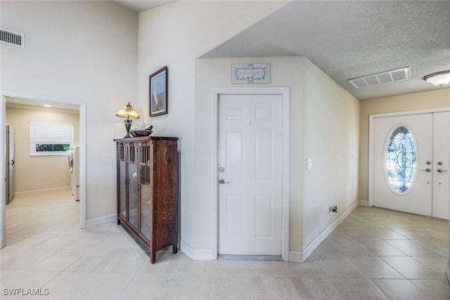 foyer entrance featuring light tile patterned flooring, baseboards, visible vents, and a textured ceiling