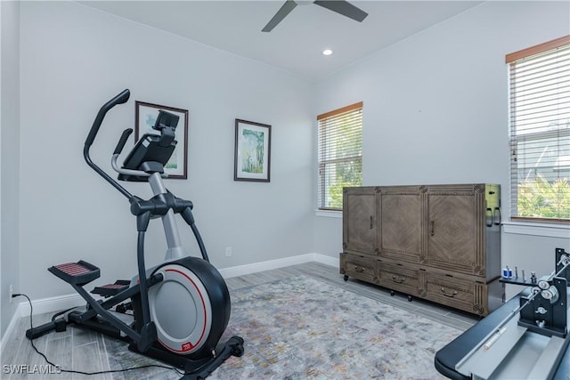 workout area with ceiling fan and light wood-type flooring