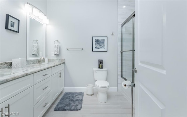 bathroom featuring vanity, tile patterned flooring, a shower with shower door, and toilet