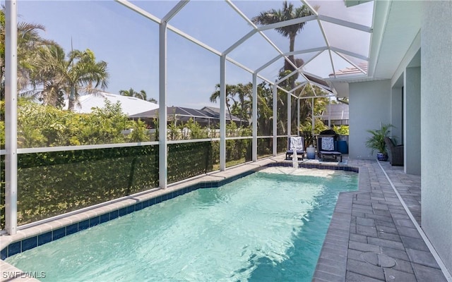 view of pool with glass enclosure and a patio area