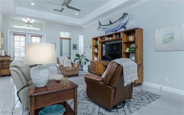 living room with a tray ceiling and ceiling fan with notable chandelier