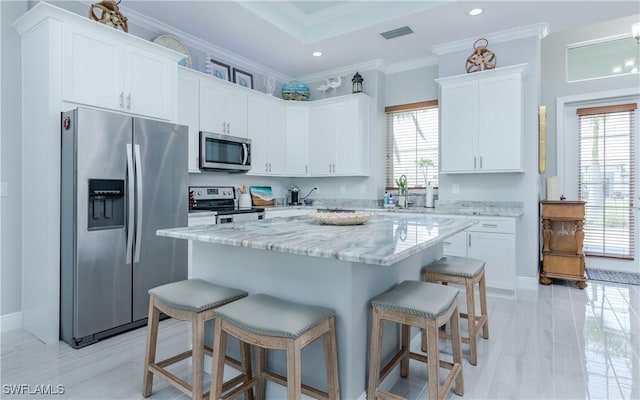 kitchen featuring white cabinetry, a kitchen breakfast bar, stainless steel appliances, and a center island