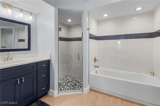 bathroom with wood-type flooring, vanity, and plus walk in shower