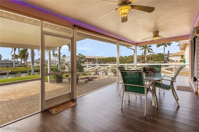 sunroom featuring plenty of natural light, a water view, and ceiling fan