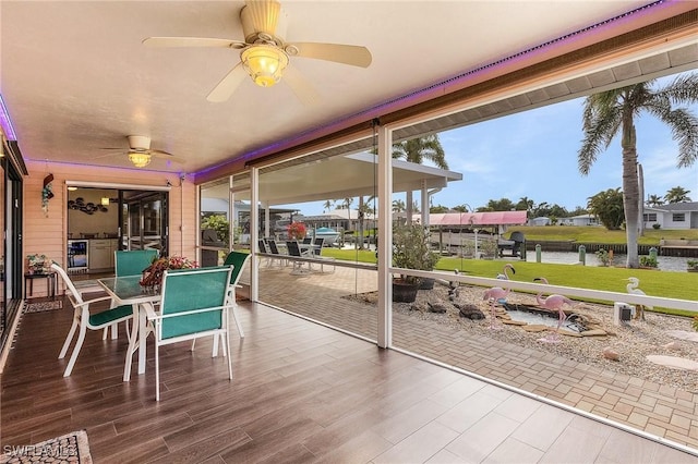 sunroom featuring ceiling fan, a water view, and a wealth of natural light