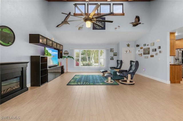 living room featuring light wood-type flooring, high vaulted ceiling, and ceiling fan