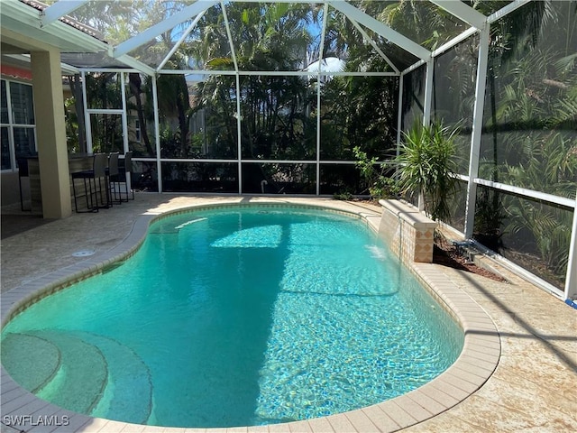 view of swimming pool with pool water feature, exterior bar, a patio area, and a lanai