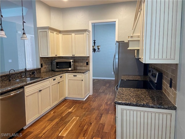 kitchen with decorative light fixtures, sink, stainless steel appliances, dark wood-type flooring, and cream cabinetry