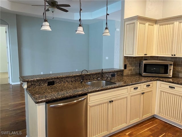 kitchen with appliances with stainless steel finishes, decorative light fixtures, sink, a raised ceiling, and cream cabinets