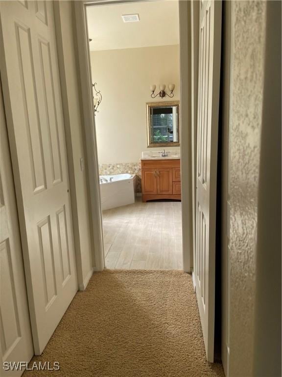 hallway featuring sink and light colored carpet