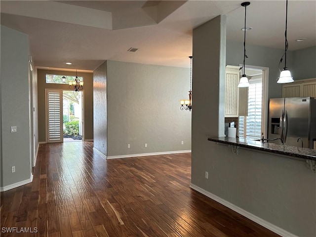 kitchen featuring stainless steel fridge with ice dispenser, a notable chandelier, dark wood-type flooring, and hanging light fixtures