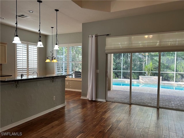 kitchen with pendant lighting, dark hardwood / wood-style floors, and a kitchen bar