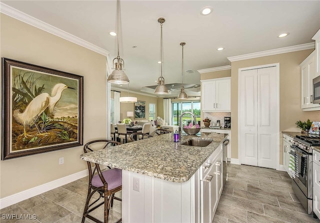 kitchen featuring light stone countertops, white cabinetry, sink, stainless steel appliances, and a center island with sink