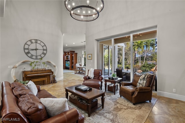 living room featuring a chandelier, a high ceiling, baseboards, light stone finish floors, and recessed lighting