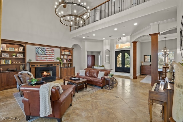 living room with decorative columns, a high ceiling, a notable chandelier, ornamental molding, and french doors