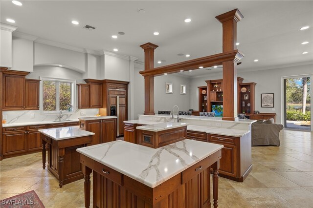 kitchen featuring a spacious island, ornamental molding, paneled fridge, recessed lighting, and a sink