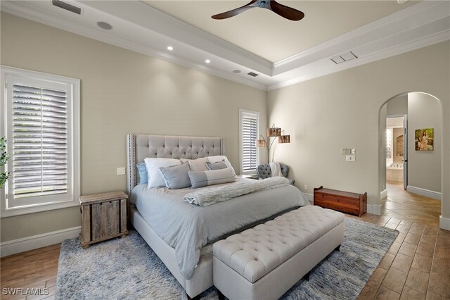 bedroom with arched walkways, crown molding, multiple windows, wood finished floors, and baseboards