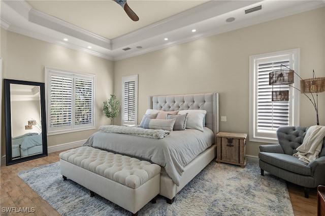 bedroom featuring crown molding, ceiling fan, a raised ceiling, and light wood-type flooring