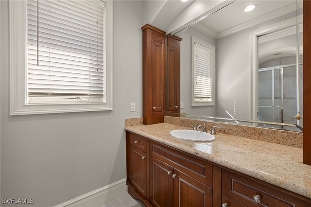 bathroom with crown molding, vanity, and a shower with door