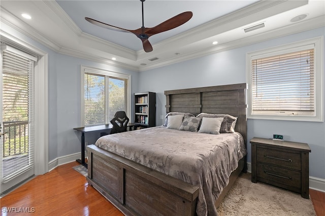 bedroom with ceiling fan, access to exterior, ornamental molding, a raised ceiling, and light wood-type flooring