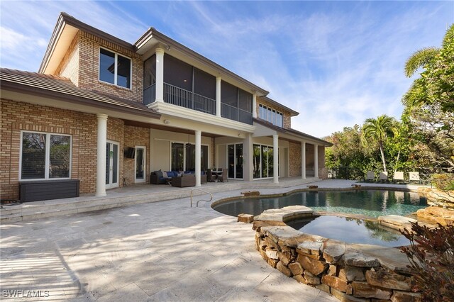 rear view of house with a swimming pool with hot tub, a patio, a sunroom, and outdoor lounge area