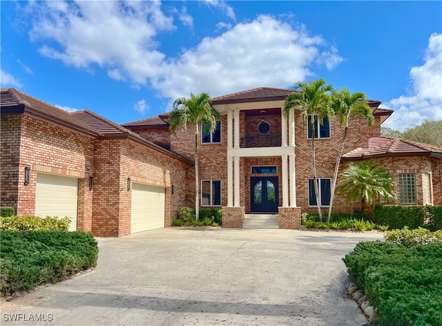 view of front facade featuring an attached garage, french doors, driveway, and brick siding