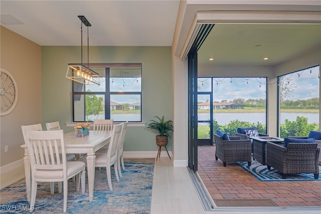 6217 Harmony Dr, Ave Maria, FL 34142 - tiled dining room with a water view, baseboards, plenty of natural light, and an inviting chandelier
