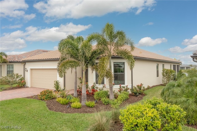 6217 Harmony Dr, Ave Maria, FL 34142 - view of front of home with an attached garage, a tile roof, stucco siding, a front lawn, and decorative driveway