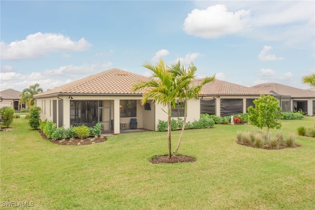 6217 Harmony Dr, Ave Maria, FL 34142 - rear view of house featuring a sunroom, a yard, stucco siding, and a tile roof