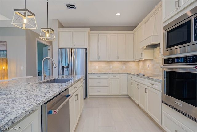 6217 Harmony Dr, Ave Maria, FL 34142 - kitchen with visible vents, white cabinets, a sink, stainless steel appliances, and backsplash