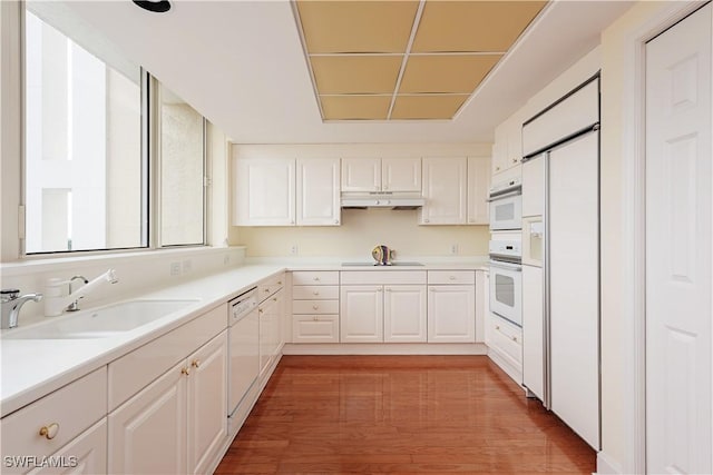 kitchen featuring white cabinetry, sink, white appliances, and light hardwood / wood-style flooring