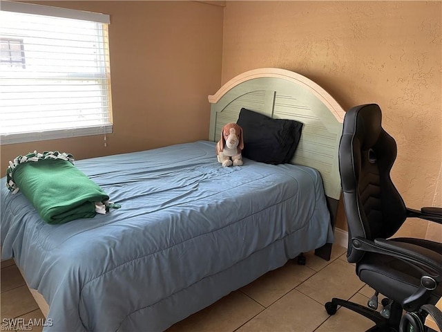 bedroom featuring light tile patterned floors and a textured wall