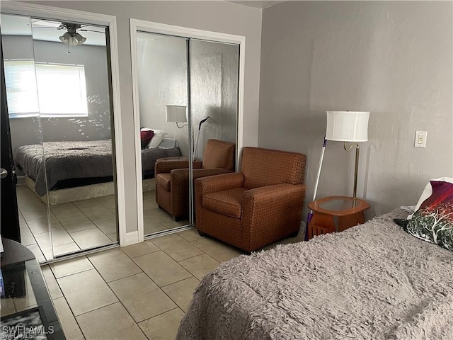 bedroom with light tile patterned floors and two closets