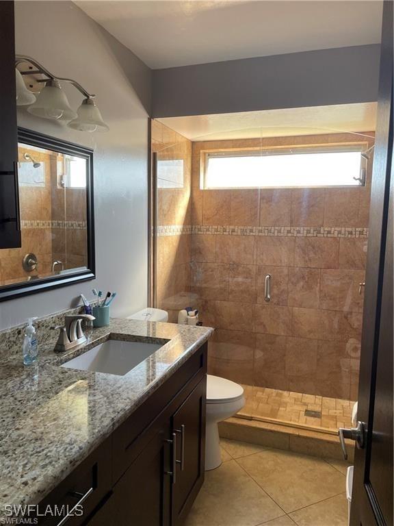 bathroom featuring vanity, toilet, a shower with door, and tile patterned flooring