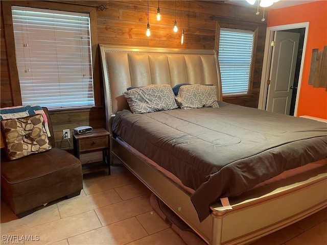 bedroom featuring light tile patterned floors and wood walls